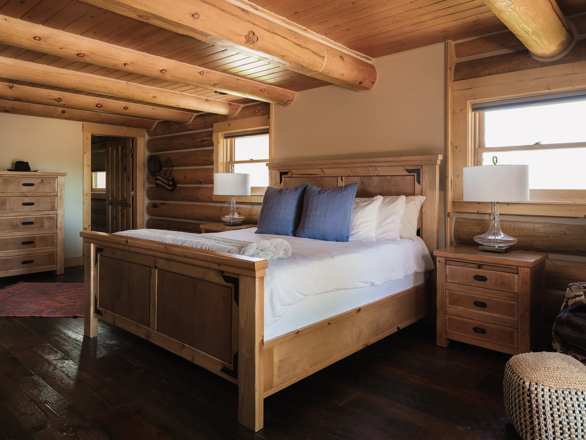 Primary bedroom with a wood bed frame and blue accent pillows — interior design photography Livingston Montana, Sam Schlauch Designs